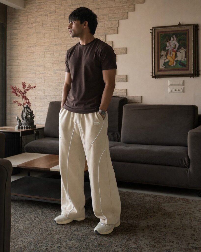 Man wearing a brown t-shirt and wide cream athletic pants in a living room