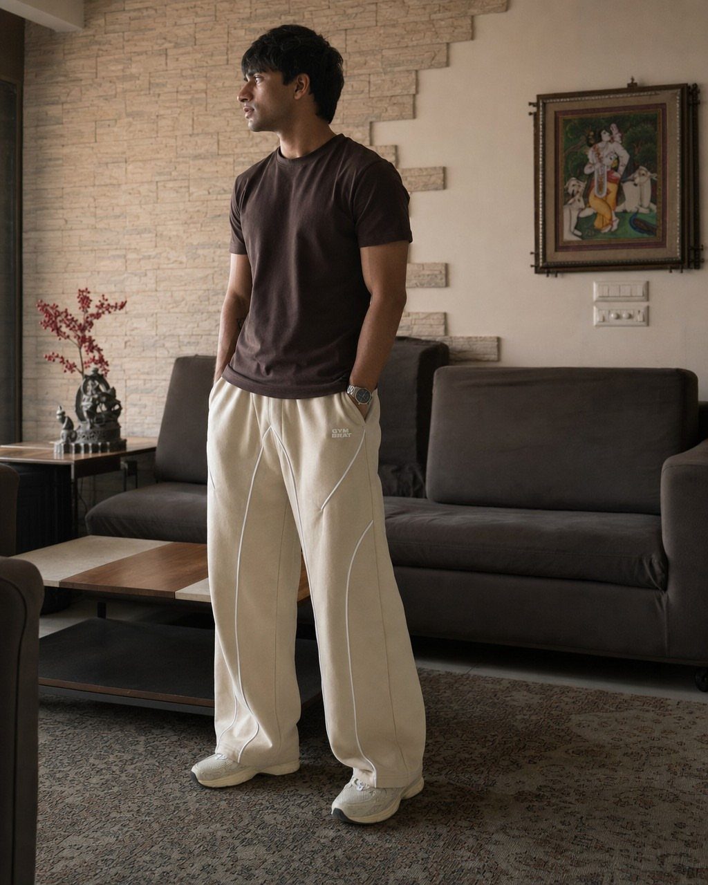 Man wearing a brown t-shirt and wide cream athletic pants in a living room