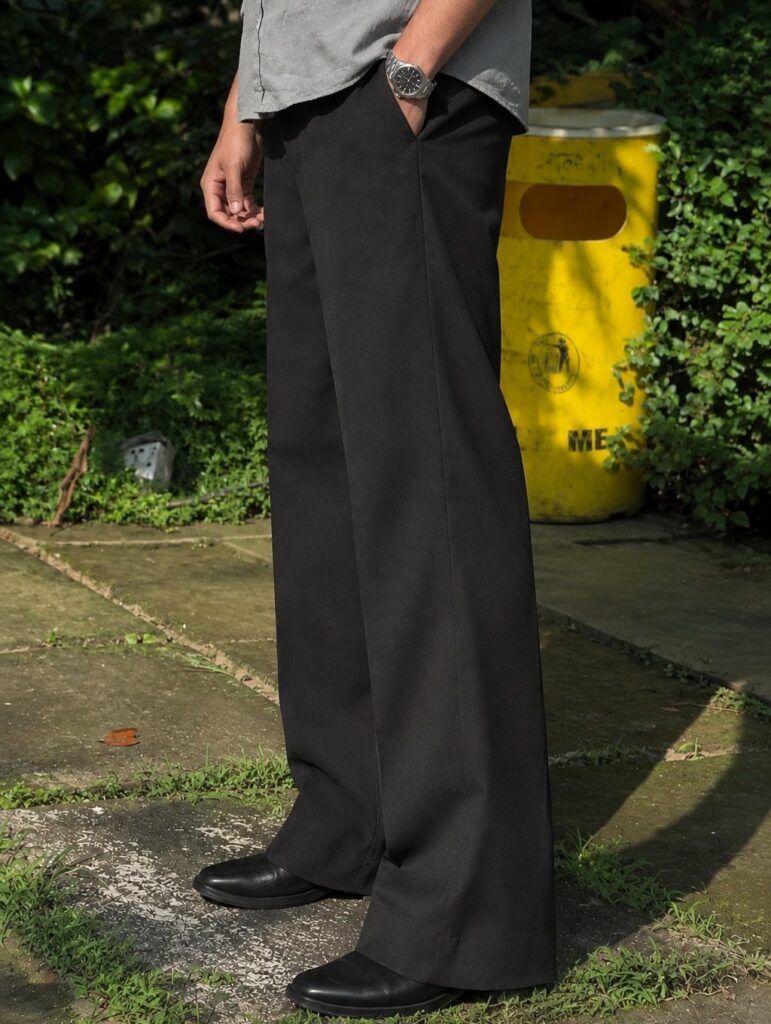 Person wearing wide-leg black trousers, grey shirt, and black leather shoes outdoors.