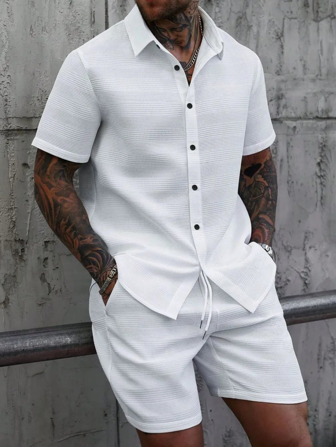Man wearing a white short-sleeved button-down shirt and matching white shorts.