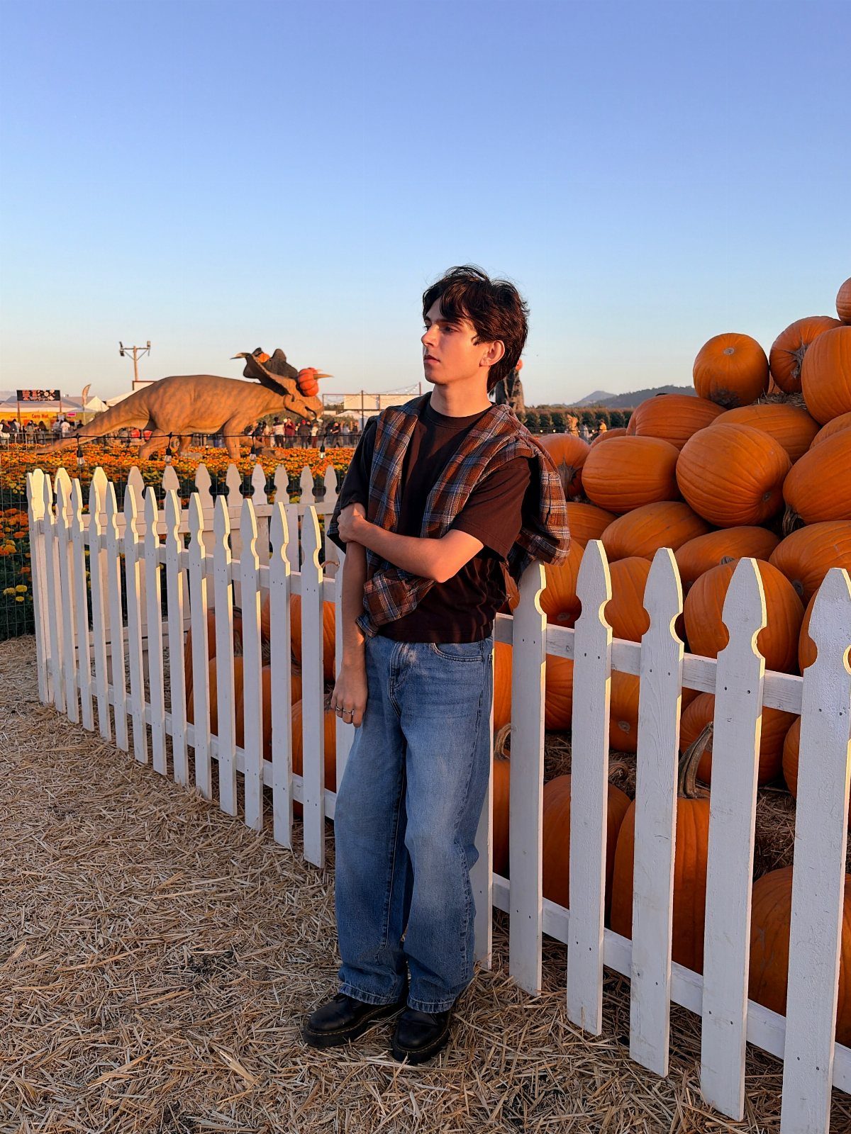 Teenage boy wearing a burnt orange plaid shirt over a dark tee and jeans.