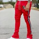 Person wearing red striped track pants, white t-shirt, and white platform sneakers.