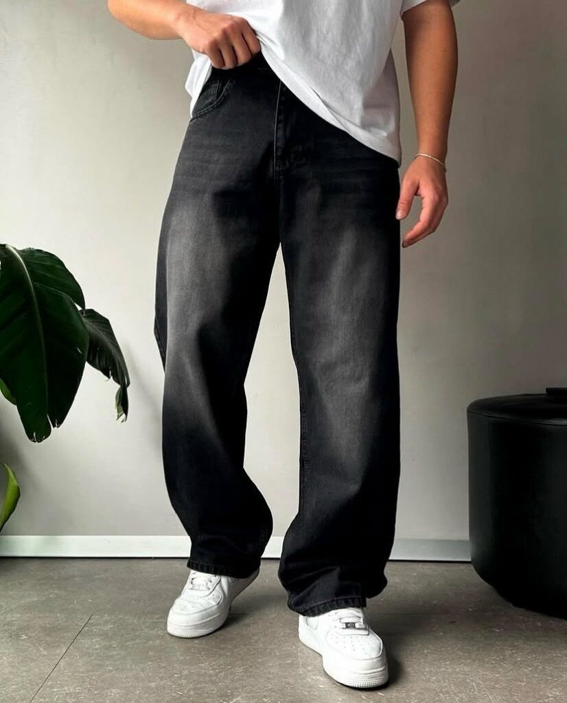 Person wearing loose black baggy jeans with a white t-shirt and white sneakers.