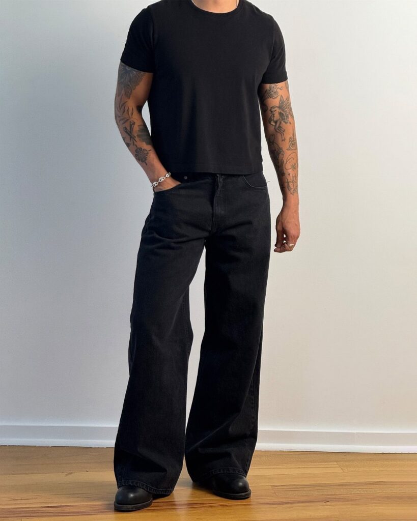 Person wearing a black fitted t-shirt and black wide-leg jeans with black shoes.